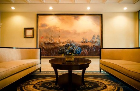 Sitting area with matching traditional upholstered sofas on opposite sides on wood coffee table and large sailing painting in background