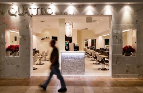 Modern hair salon in mall, entrance elevation with blurred person walking by. walls in white marble, cream color floors