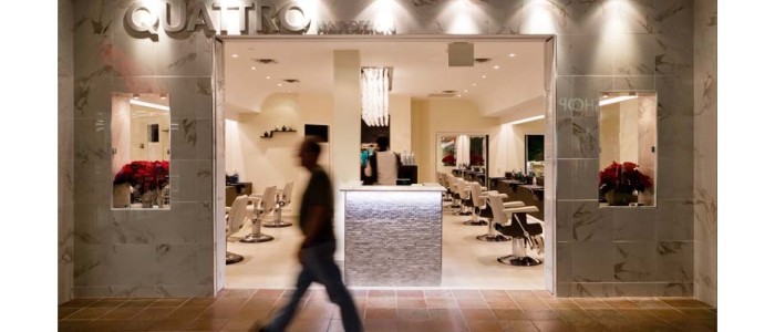 Modern hair salon in mall, entrance elevation with blurred person walking by. walls in white marble, cream color floors