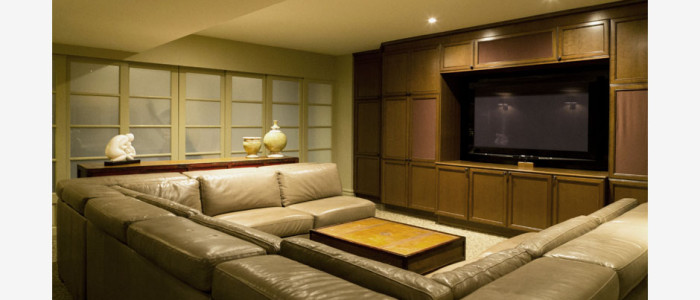 Recreation room AV cabinet in walnut. c shape leather sofa and pine coffee / sofa table, opaque doors beyond