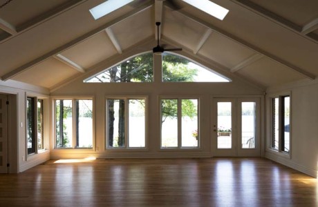 great room vaulted ceiling and skylights. Large arched window extending from top of lower bank of windows and doors into vaulted ceiling to form a wall off glass facing the lake