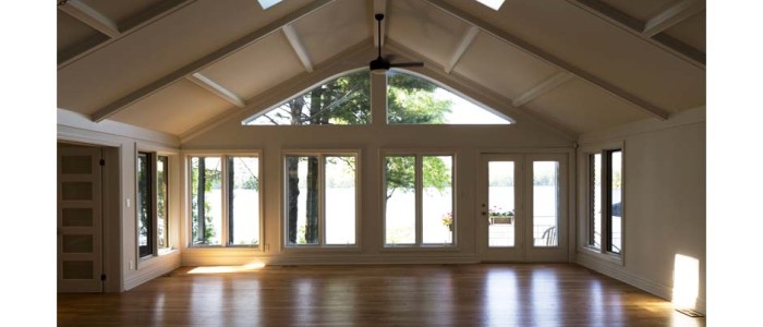 great room vaulted ceiling and skylights. Large arched window extending from top of lower bank of windows and doors into vaulted ceiling to form a wall off glass facing the lake