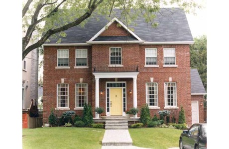 Classically laid out red brick 2 story home with yellow entry door, columns and portico in white