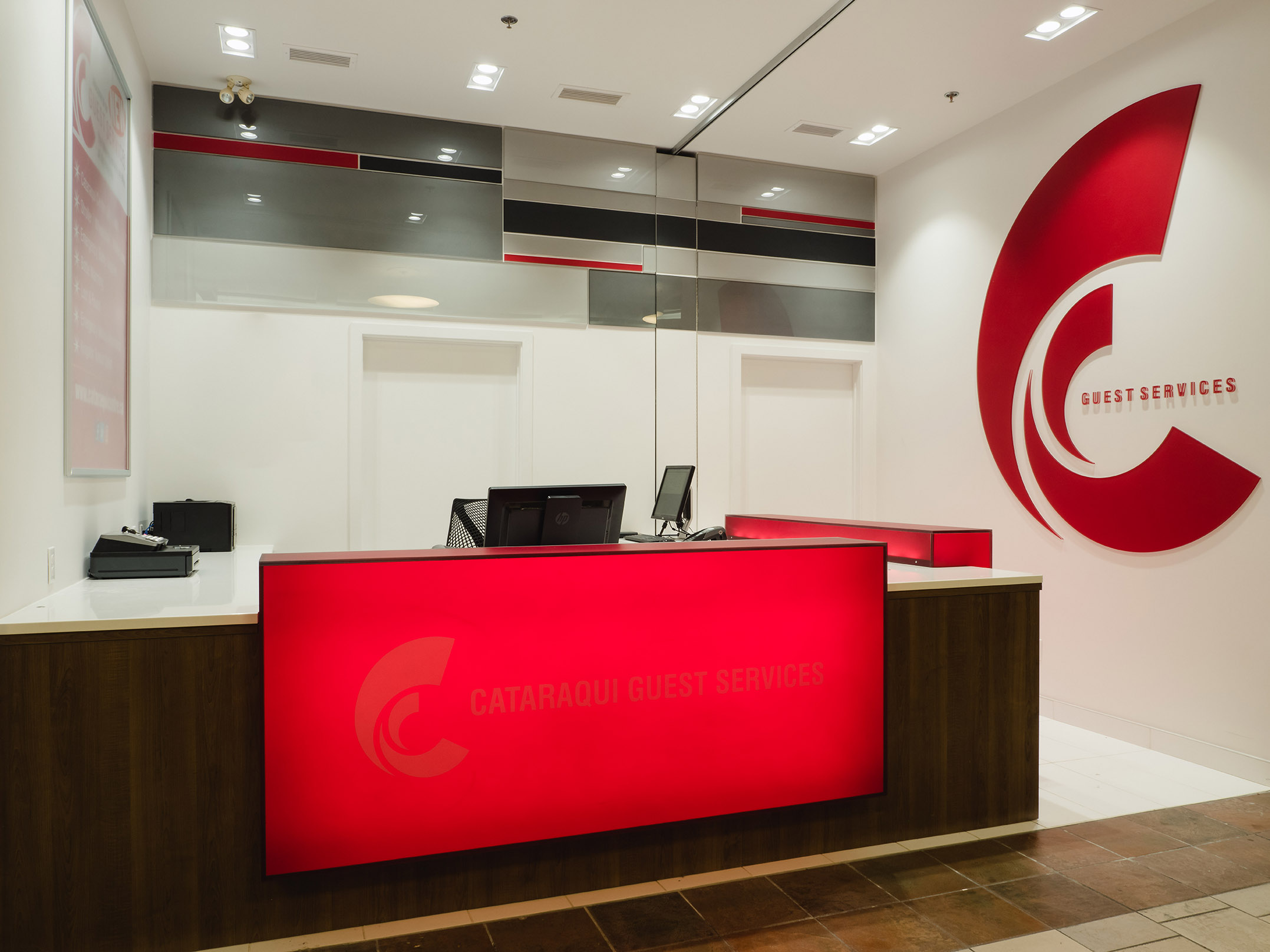 Wide view of Cataraqui Centre’s guest services desk with glowing red signage and backlit service board.