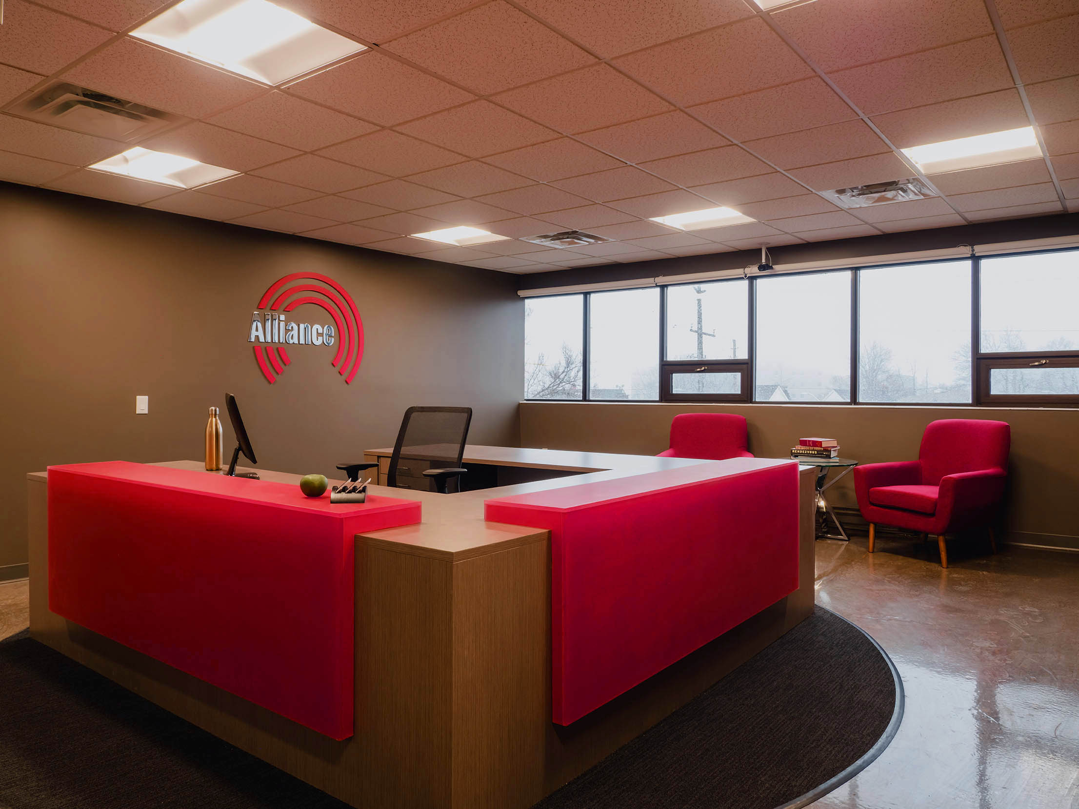 Detail of the Alliance reception desk featuring backlit red panels and warm wood tones.