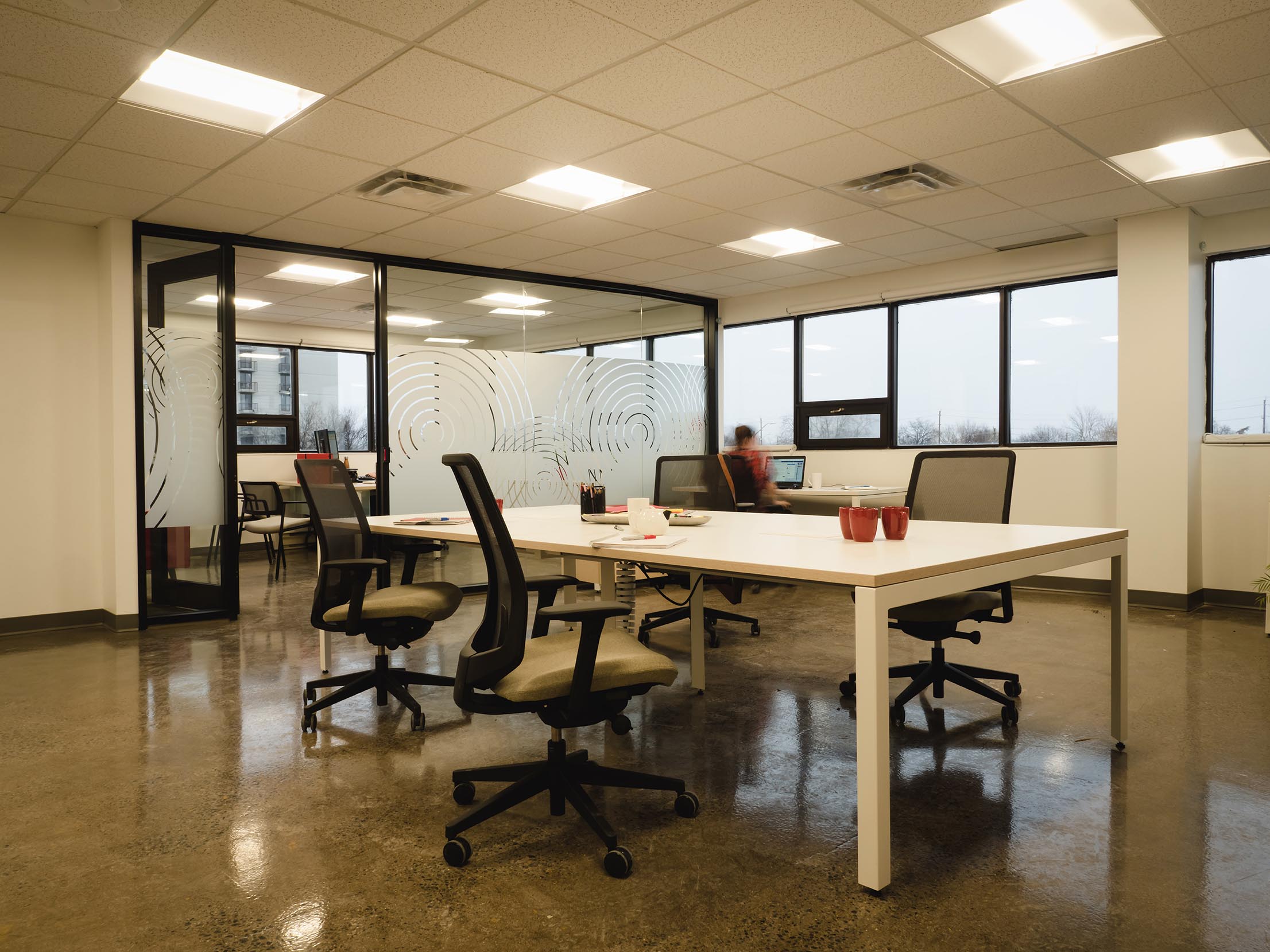 Lounge-style meeting zone with sectional seating, bar-height table, and panoramic windows.