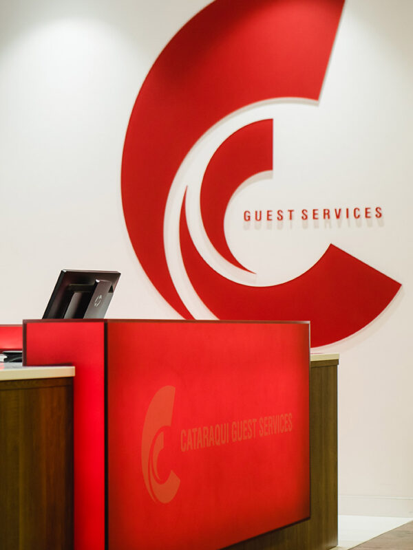 view of Cataraqui Centre’s guest services desk with glowing red signage and backlit service board