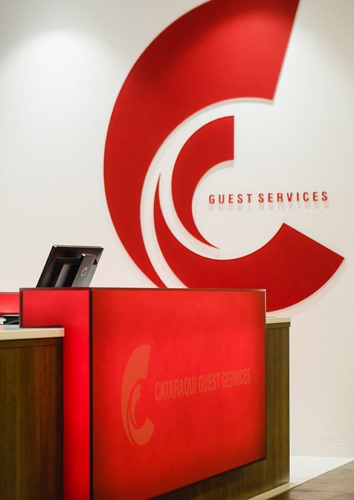 view of Cataraqui Centre’s guest services desk with glowing red signage and backlit service board