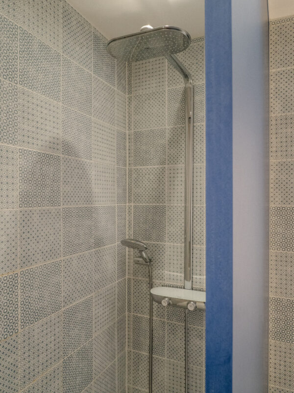 Unique powder room with pastel blue feature wall, perforated tile design, and matte black hardware for a crisp modern contrast