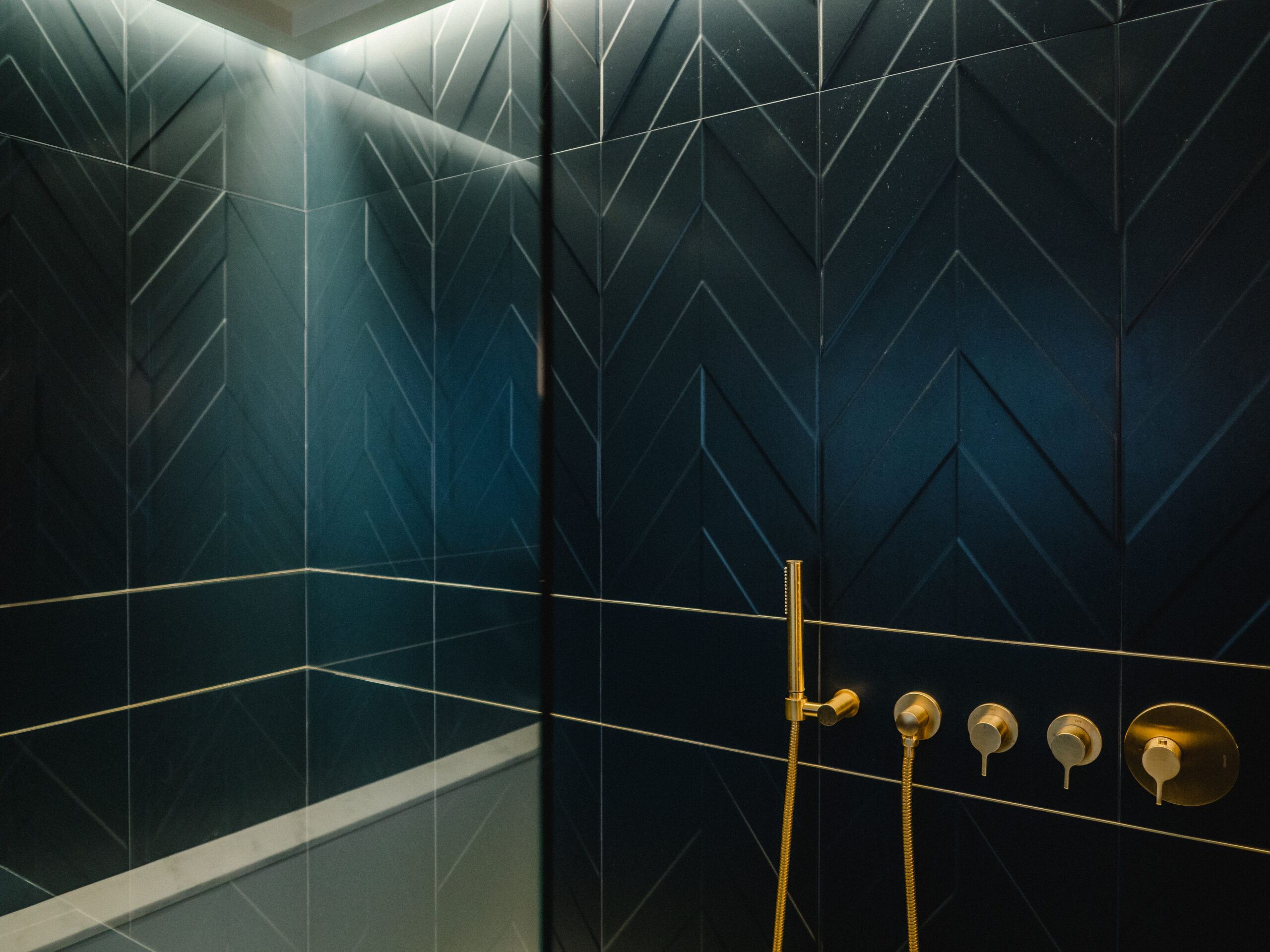 Brass shower fixtures on blue patterned tile
