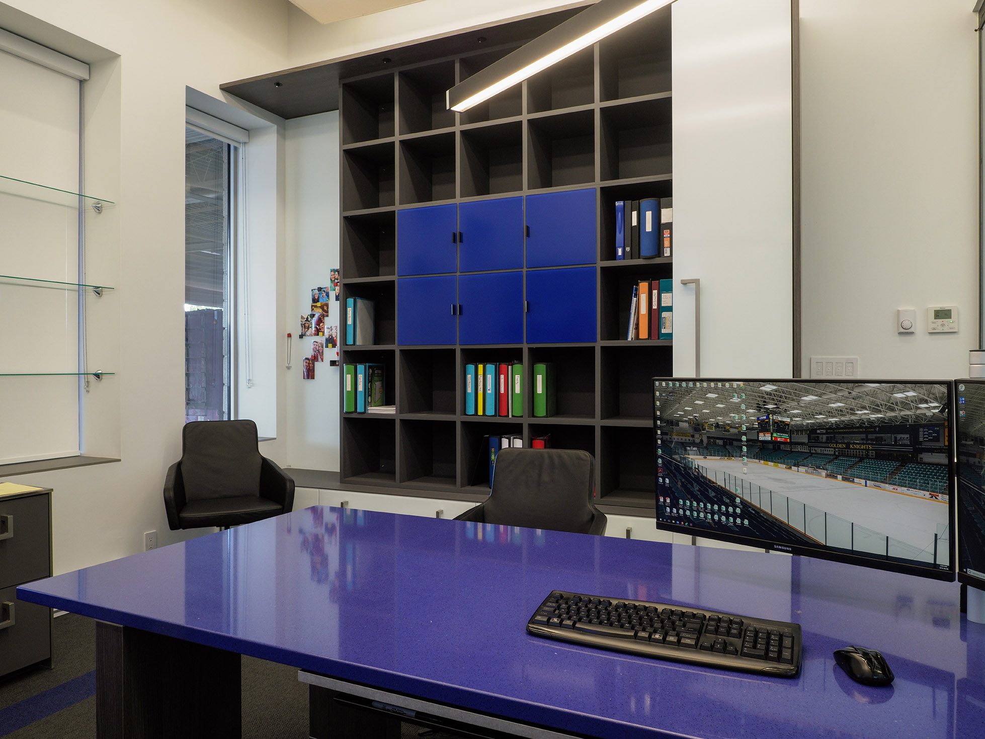 Contemporary office featuring a striking blue quartz desk, integrated wall storage with blue accents, and personal touches displayed on adjacent walls.