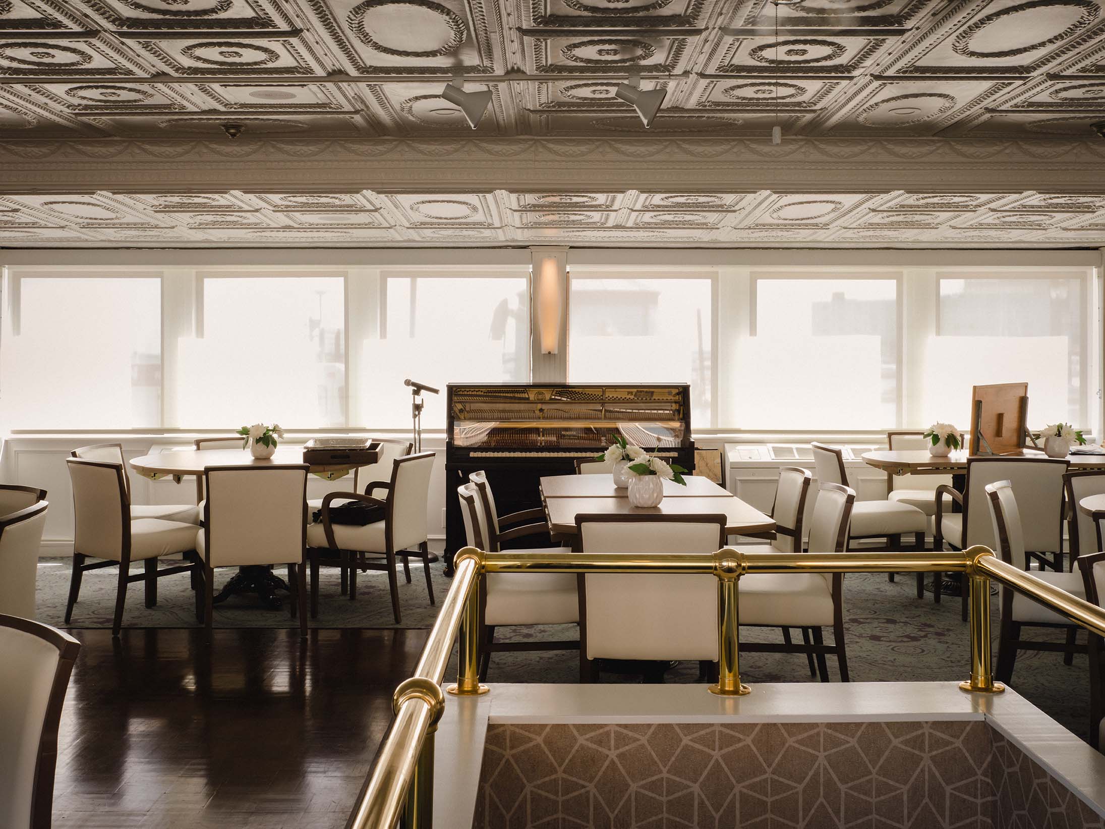 Formal dining area with brass railings and classic tin ceiling panels aboard historic river cruise ship