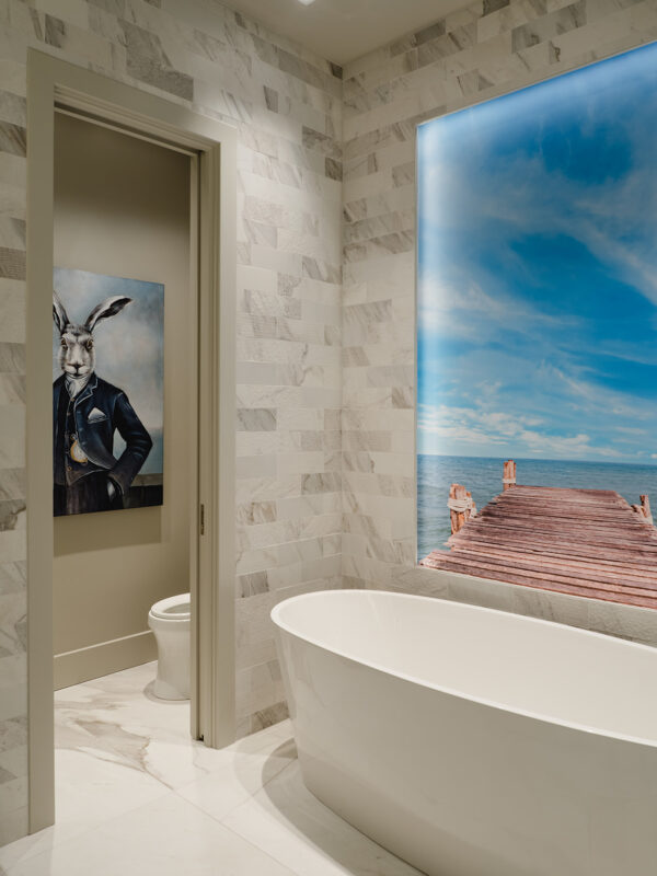 Freestanding bathtub with feature lighting and framed art as focal point