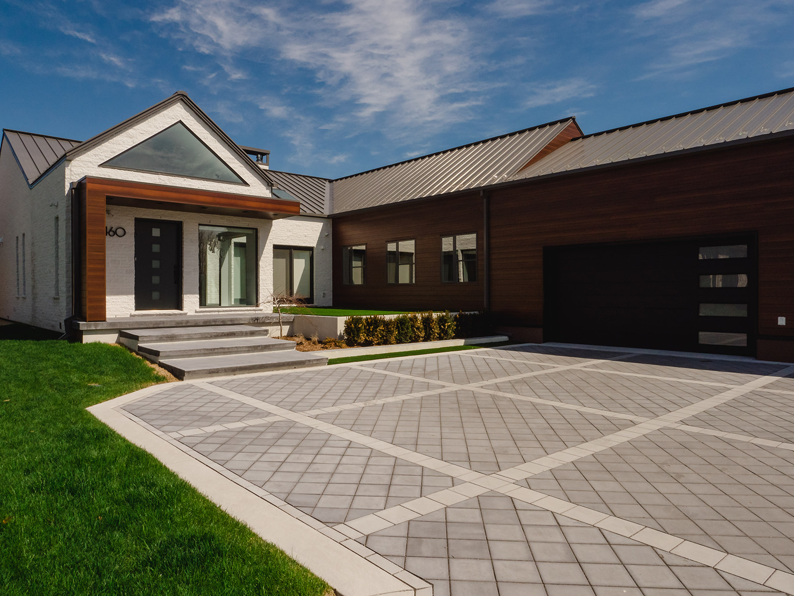 Modern custom home with white stone, wood siding, and large-format windows