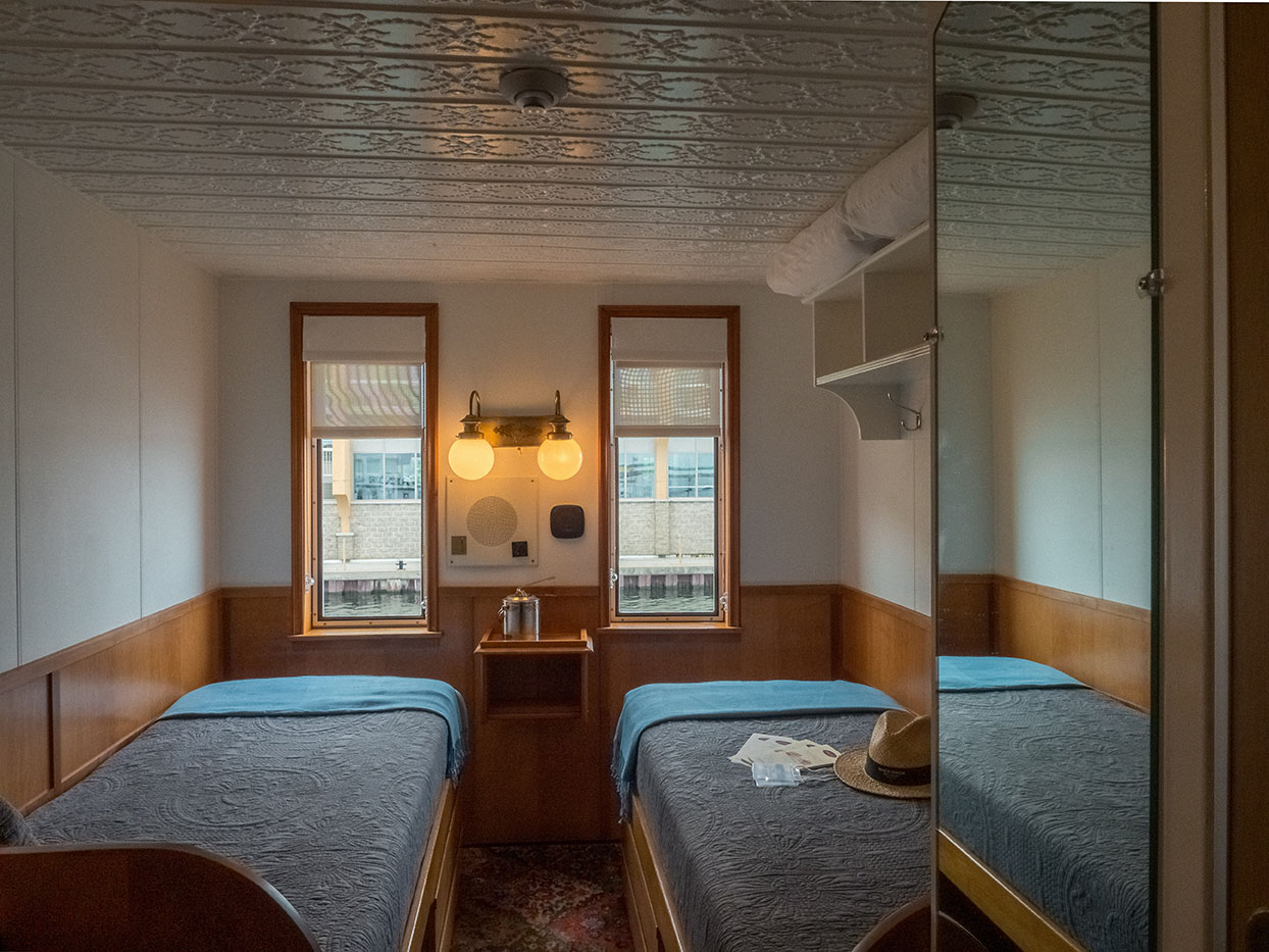 Charming cabin interior with vintage light fixture, twin beds, and waterfront view