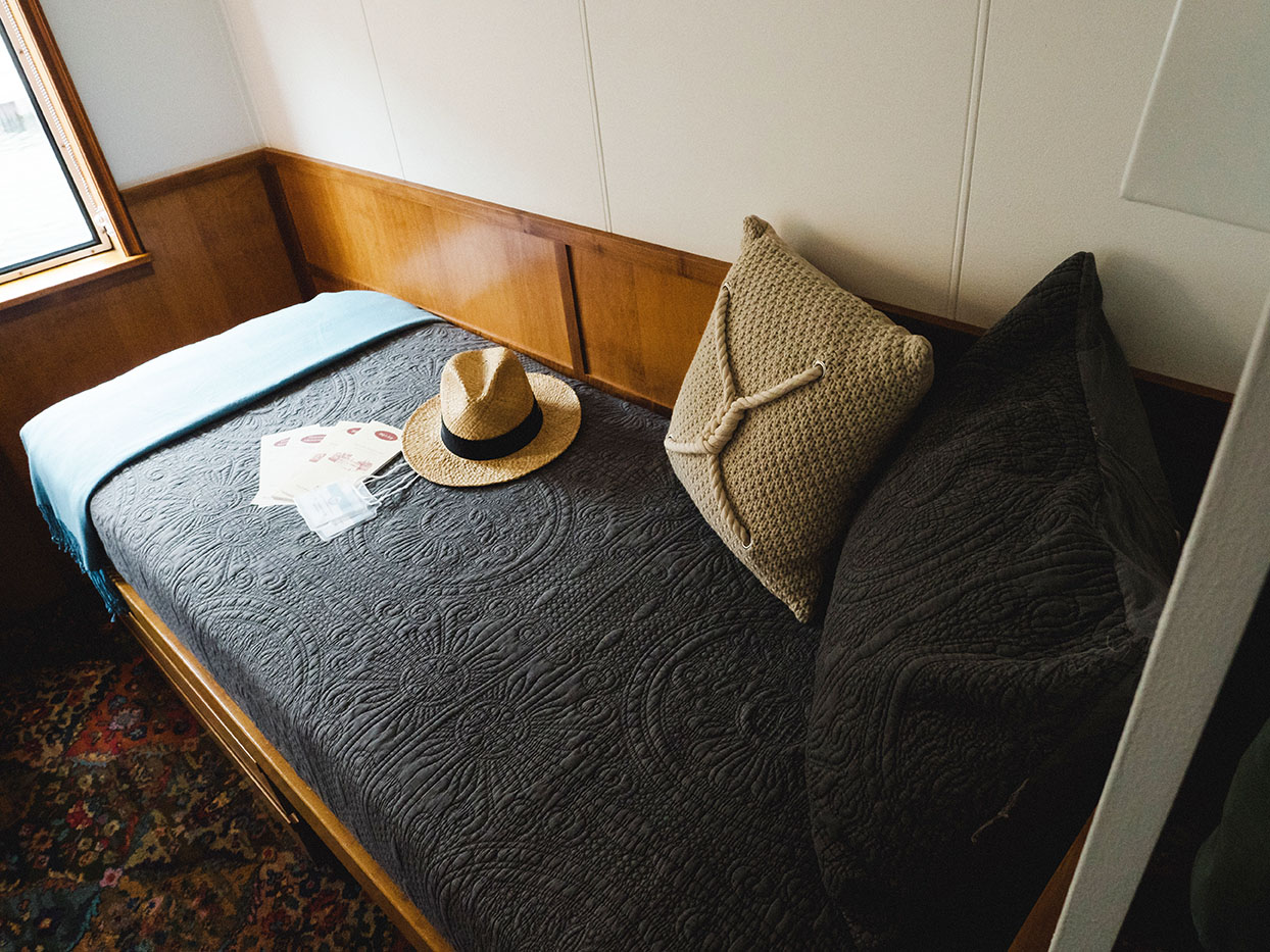 Cozy guest suite with single bed, white upper shelving, and custom millwork
