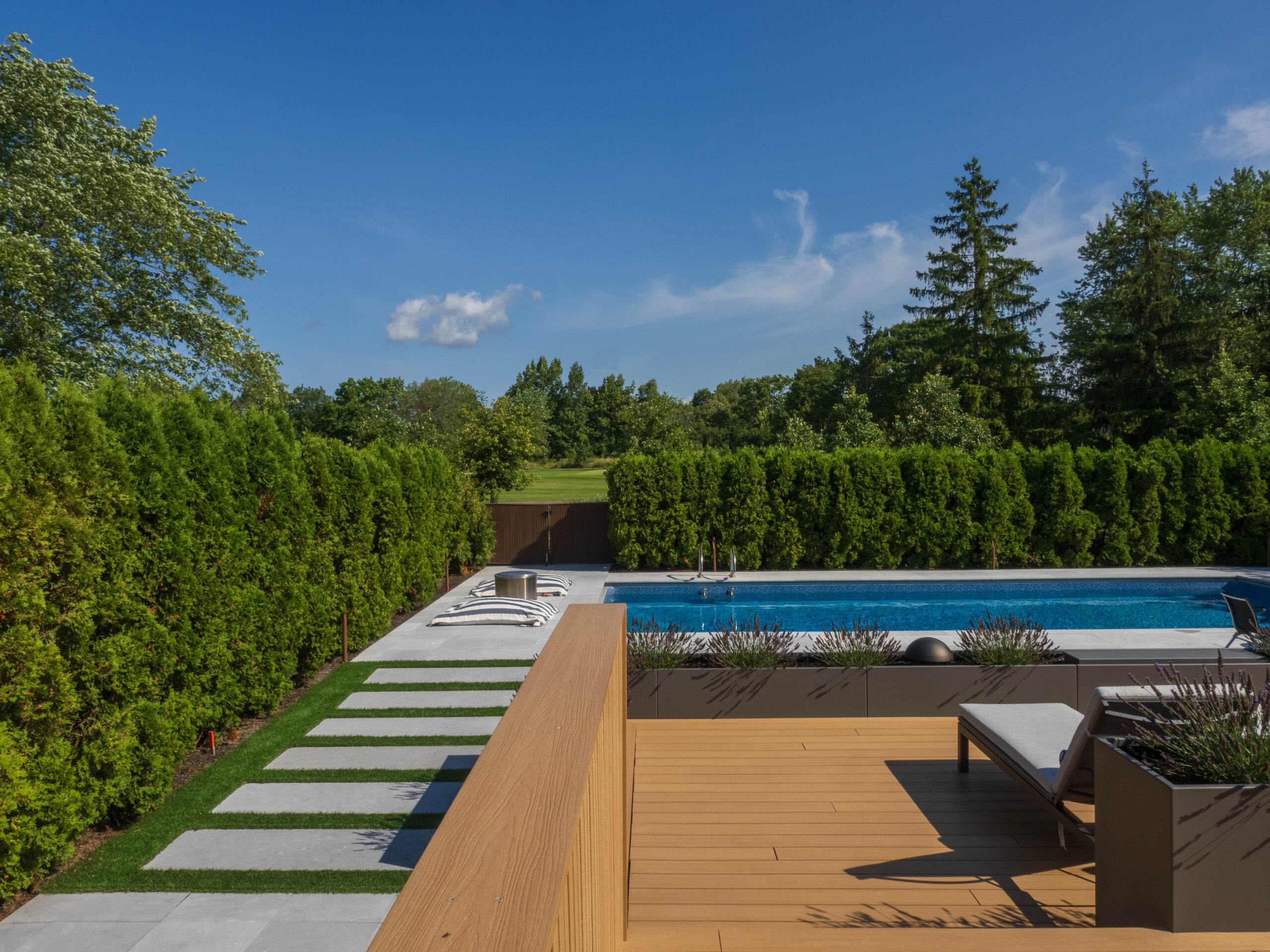 limestone paver path to pool surrounded by green hedge
