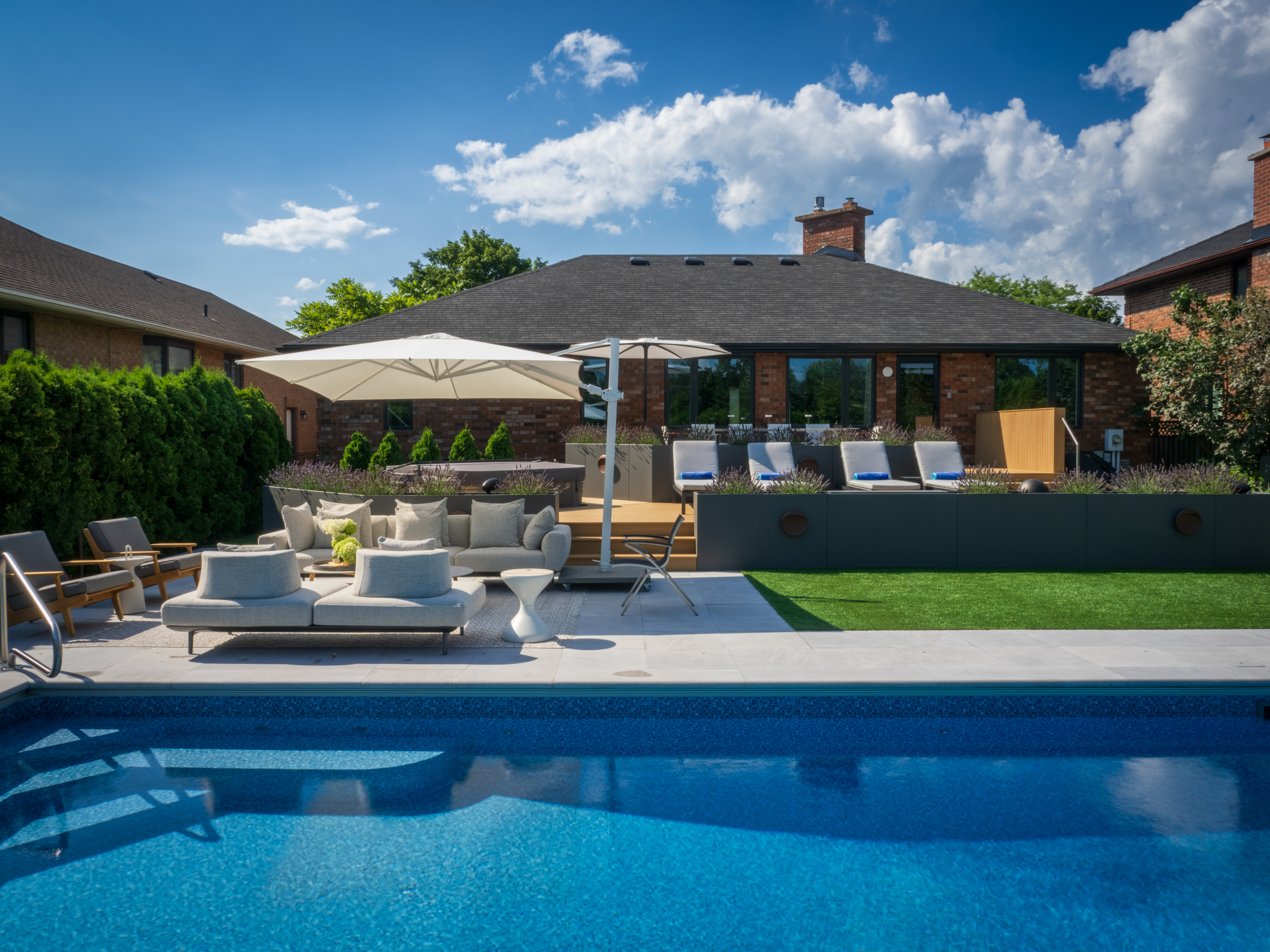 Backyard retreat featuring sleek pool, deck, and layered entertaining zones
