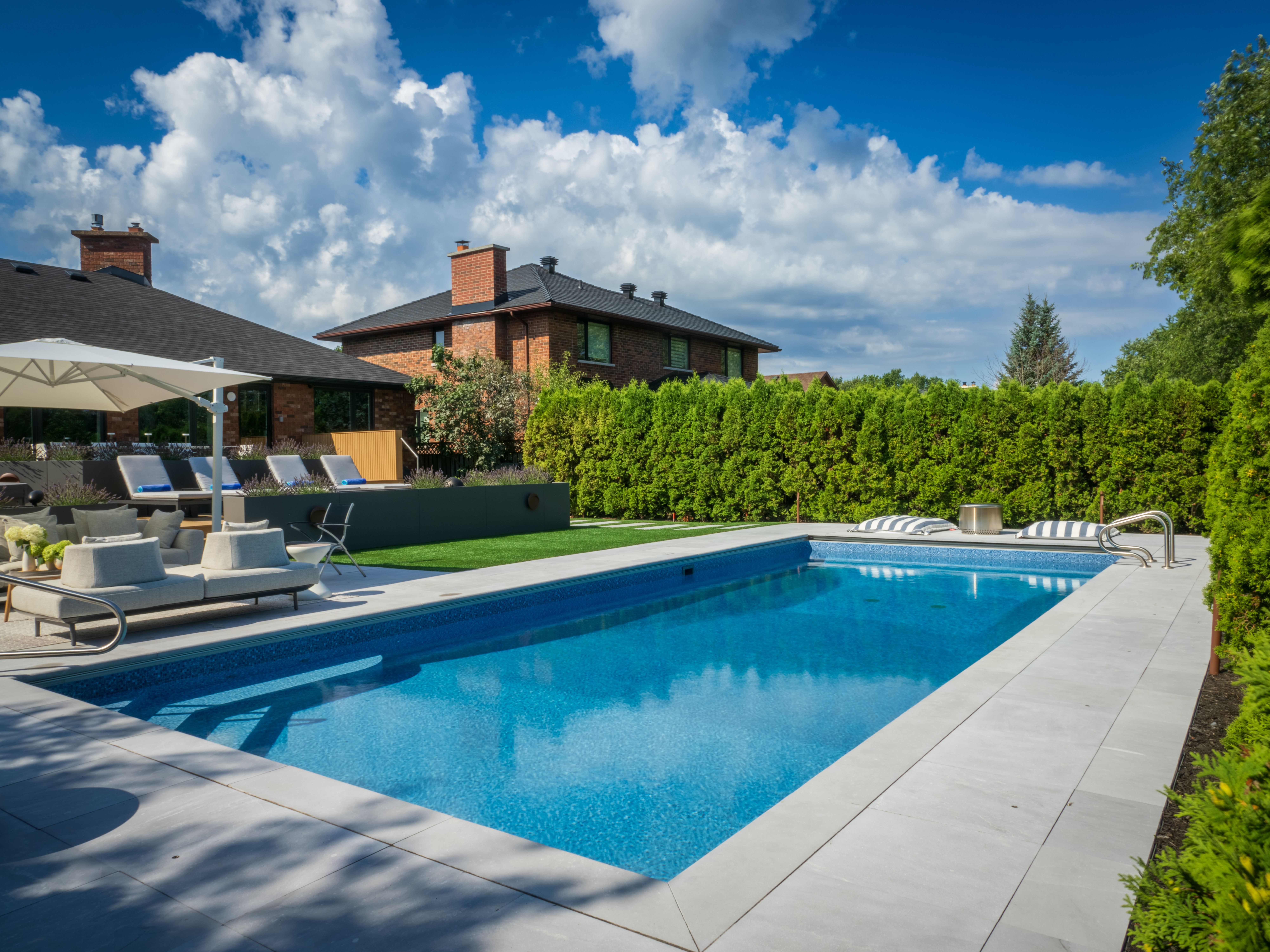 Modern rectangular pool surrounded by large-format limestone patio