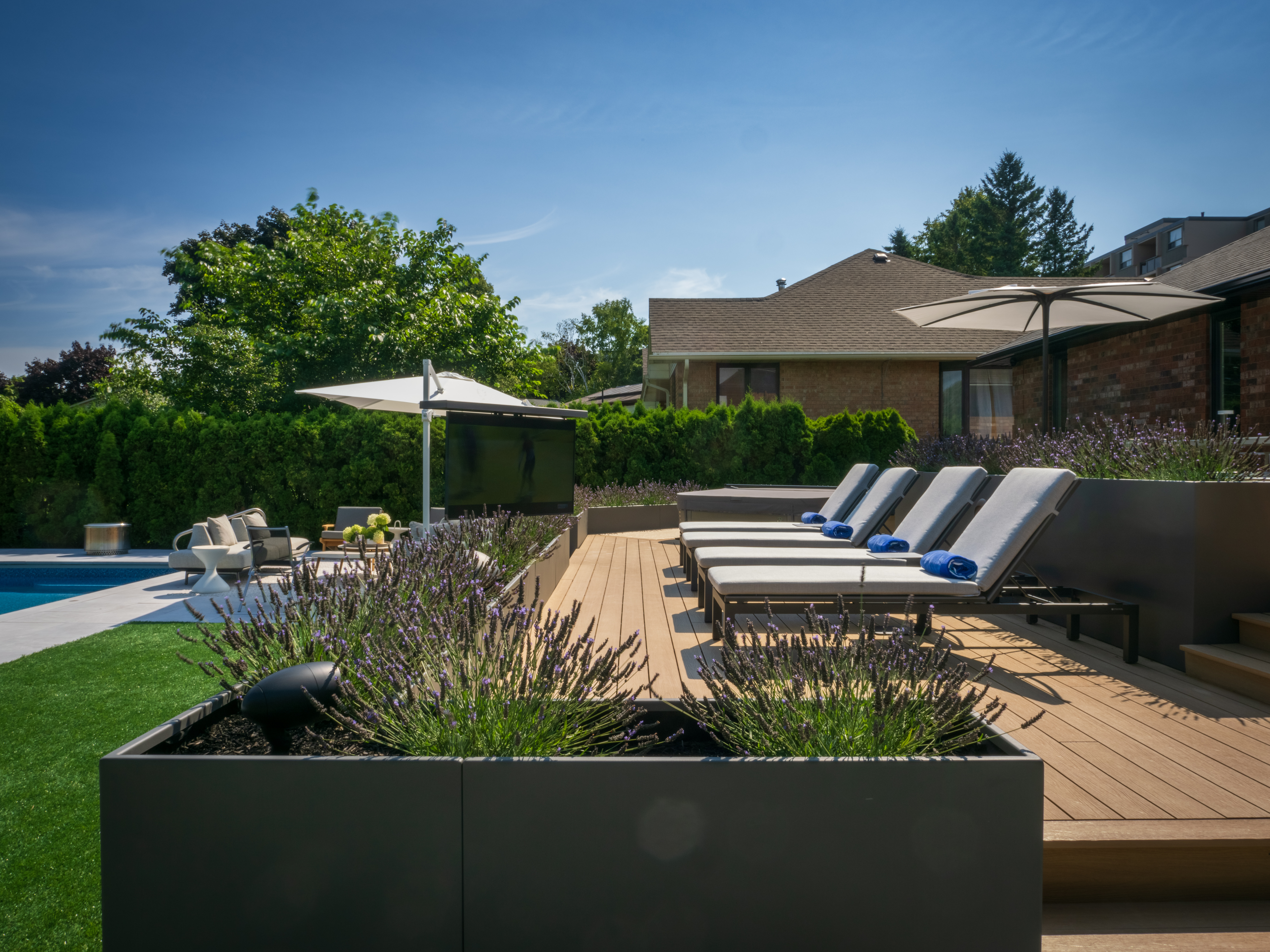 Poolside lounge area with outdoor sofas, umbrella, and modern planters