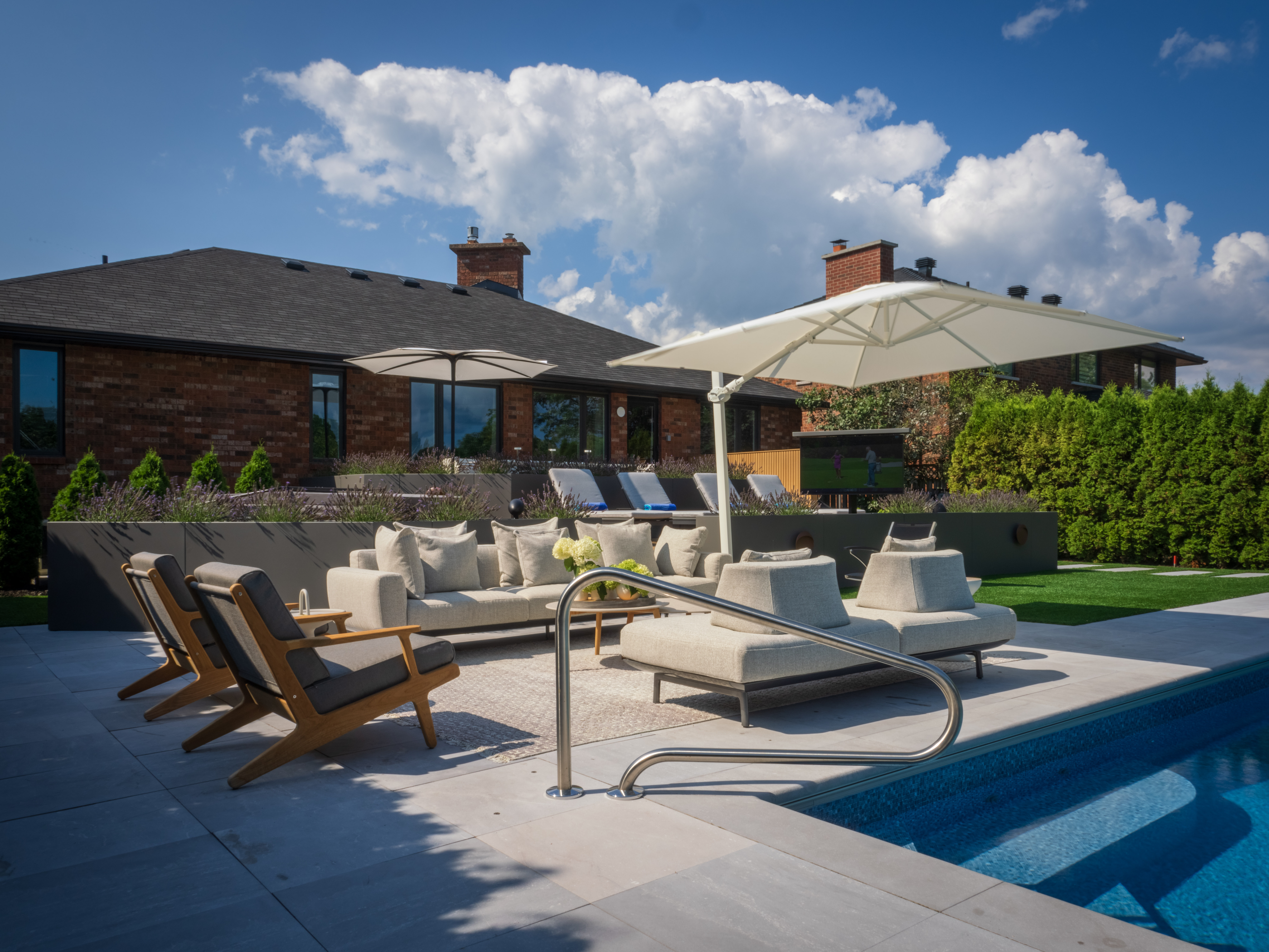 Modern outdoor lounge with cushioned sofas, low chairs, and white umbrella
