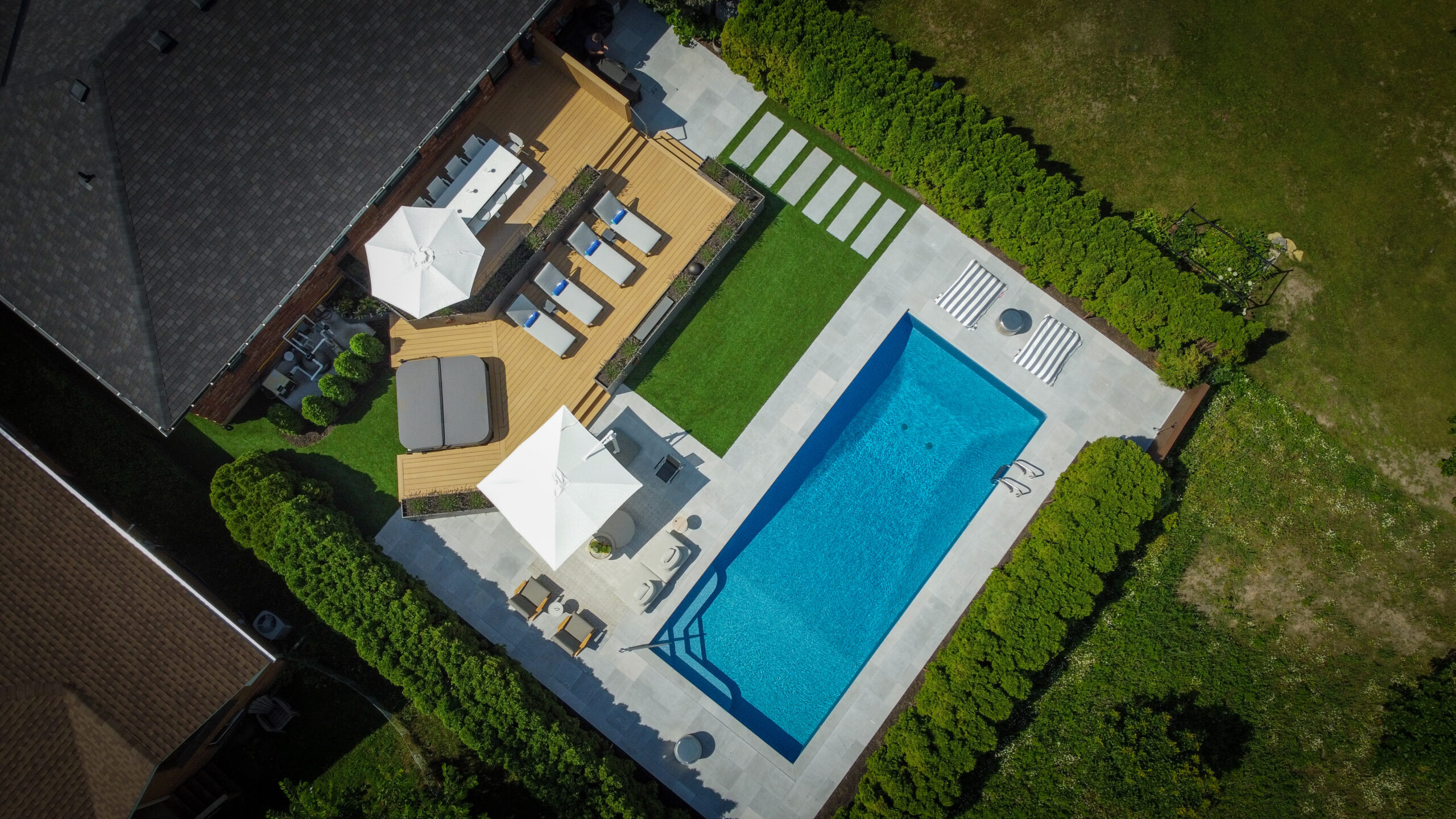 Overhead view of modern backyard with rectangular pool and two-tiered deck