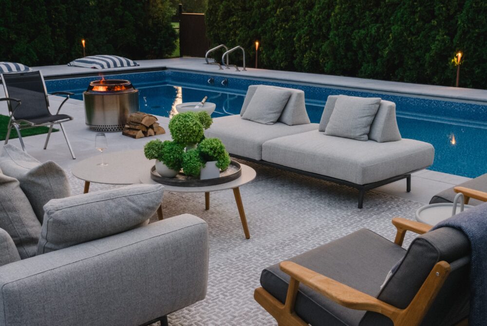 Poolside lounge area with outdoor sofas, umbrella, and modern planters
