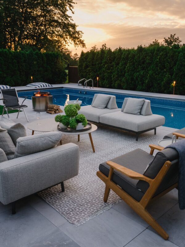 Poolside lounge area with outdoor sofas, umbrella, and modern planters
