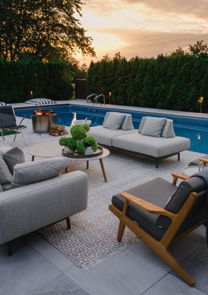 Poolside lounge area with outdoor sofas, umbrella, and modern planters