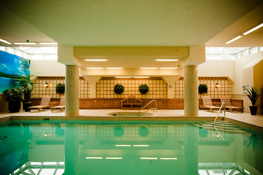 Indoor pool and lounge area with wood trellis walls and potted plants in a condominium