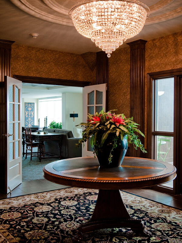 Grand entry table beneath a crystal chandelier in a richly styled condominium lobby