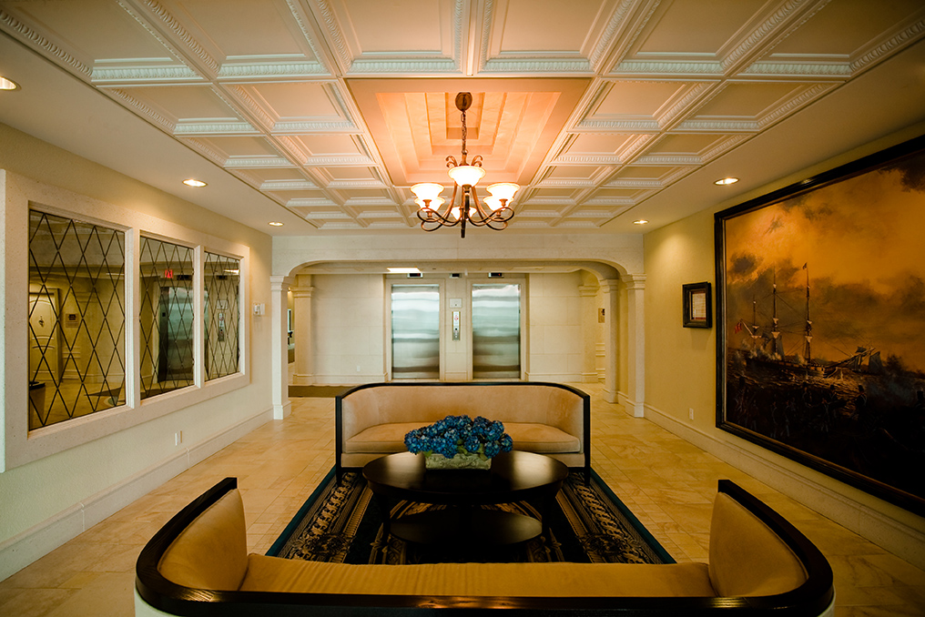 Formal condominium lobby with coffered ceiling, custom seating, and large maritime painting
