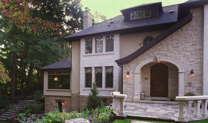 Front elevation of a timeless custom-built stone and stucco home in Toronto, perched above a wooded ravine