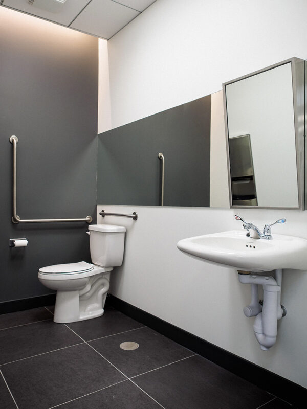Fully accessible washroom with sleek grey and white finishes and grab bars.