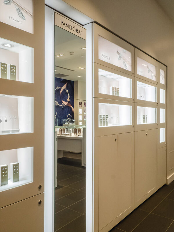 Vertical display and mirror detail flanked by illuminated jewelry niches and signage for earrings.