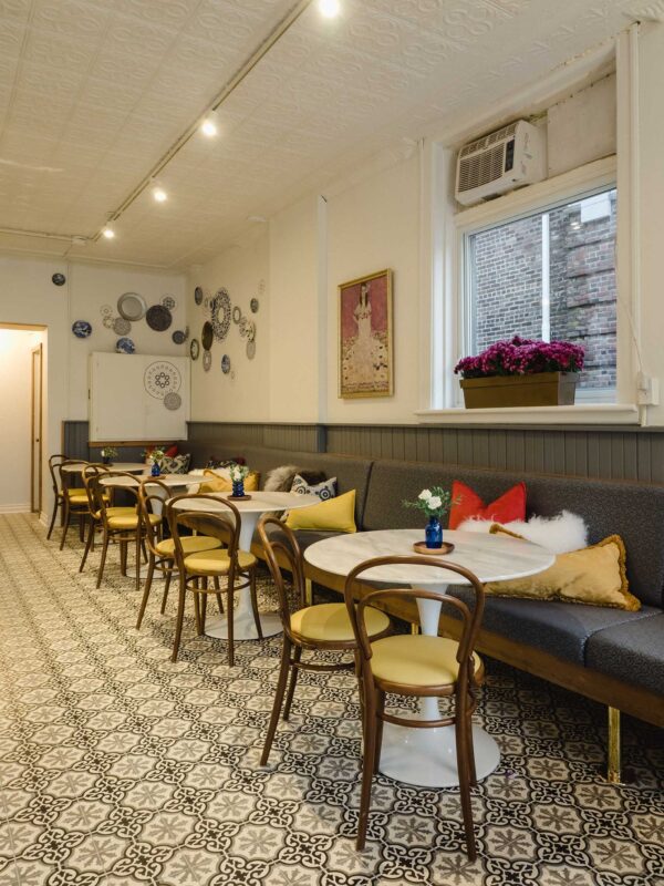 Interior view of The Vic Café showing patterned floor tiles, banquette seating, and decorative wall plates