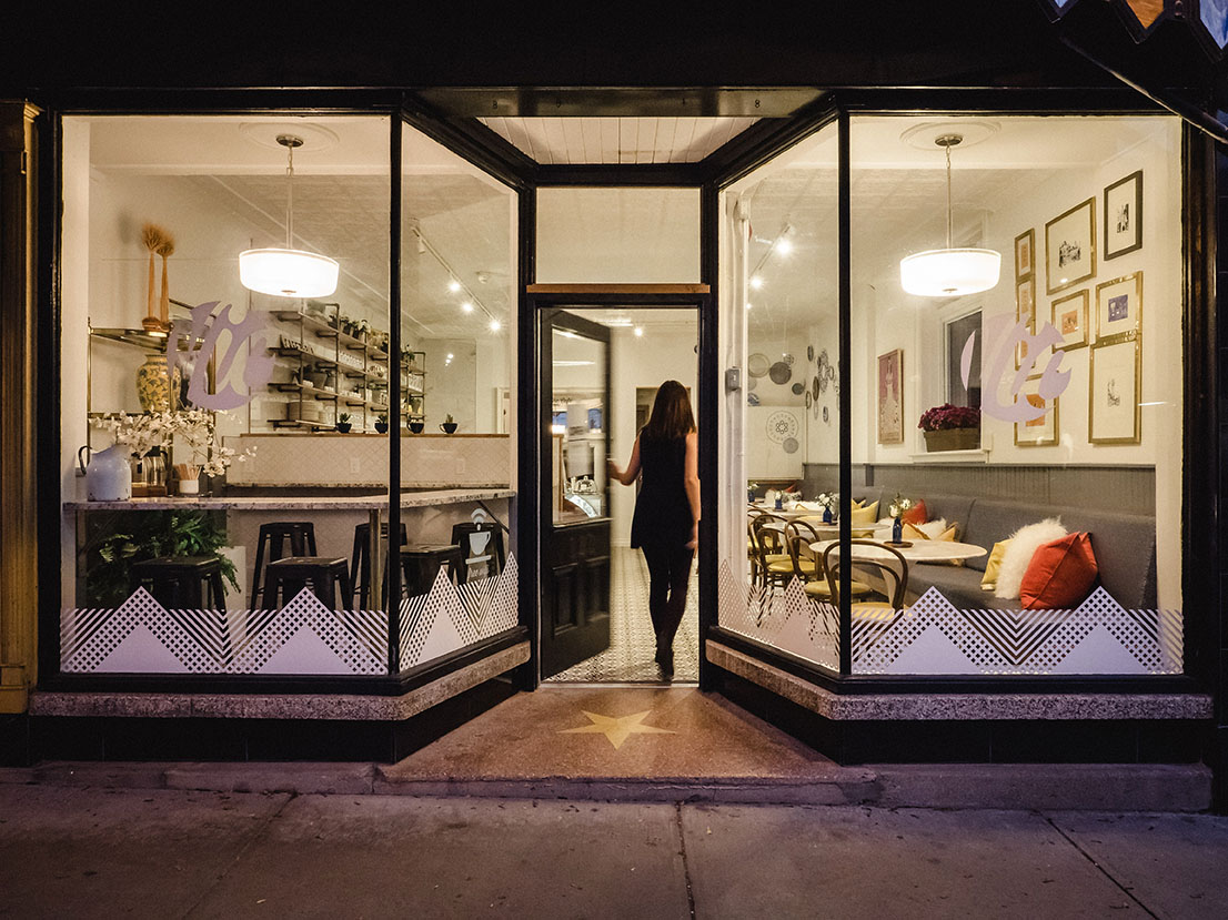 Exterior nighttime view of The Vic Café with warm lighting and modern window graphics.
