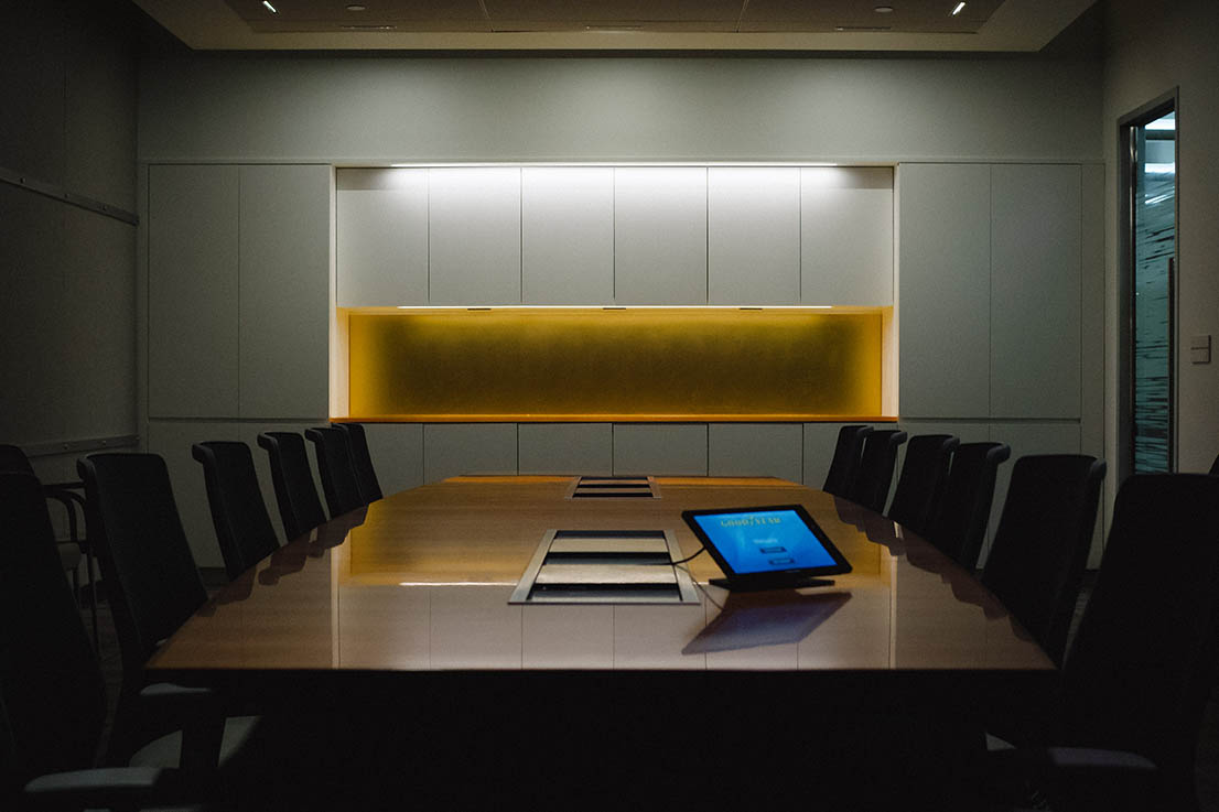 View of boardroom millwork with orange accent counter and doorway featuring frosted glass privacy treatment.