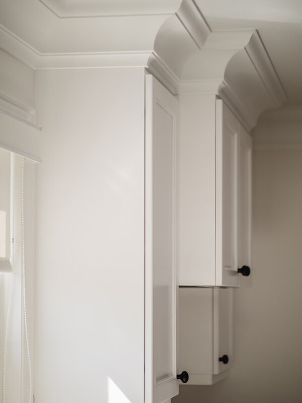 Detail of stacked upper cabinetry with decorative crown moulding in a transitional kitchen design.