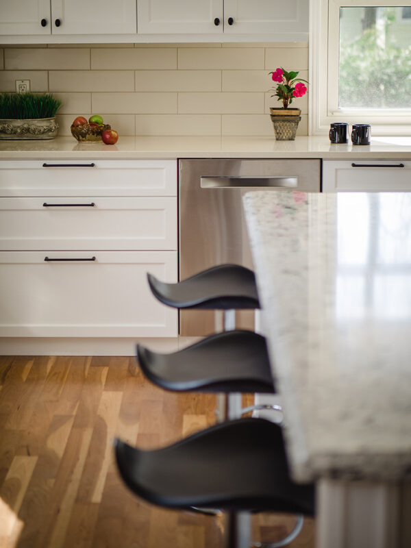 Close-up of bar stools along the island in a transitional kitchen with warm hardwood flooring and soft natural light.