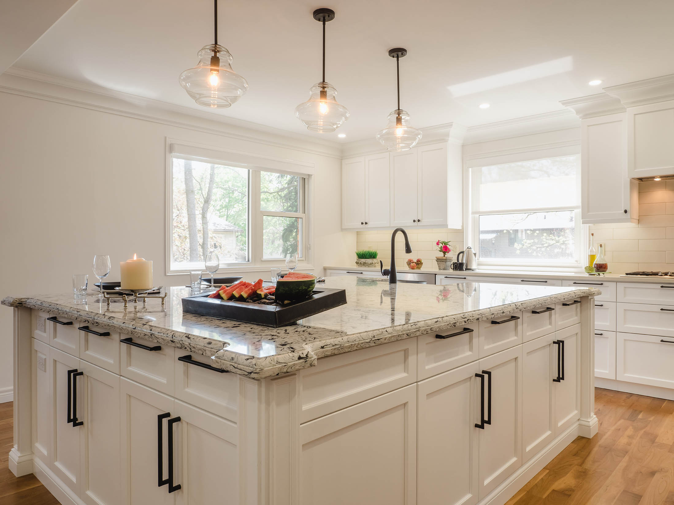 View of custom kitchen island showcasing applied panels, base trim details, and natural hardwood flooring.
