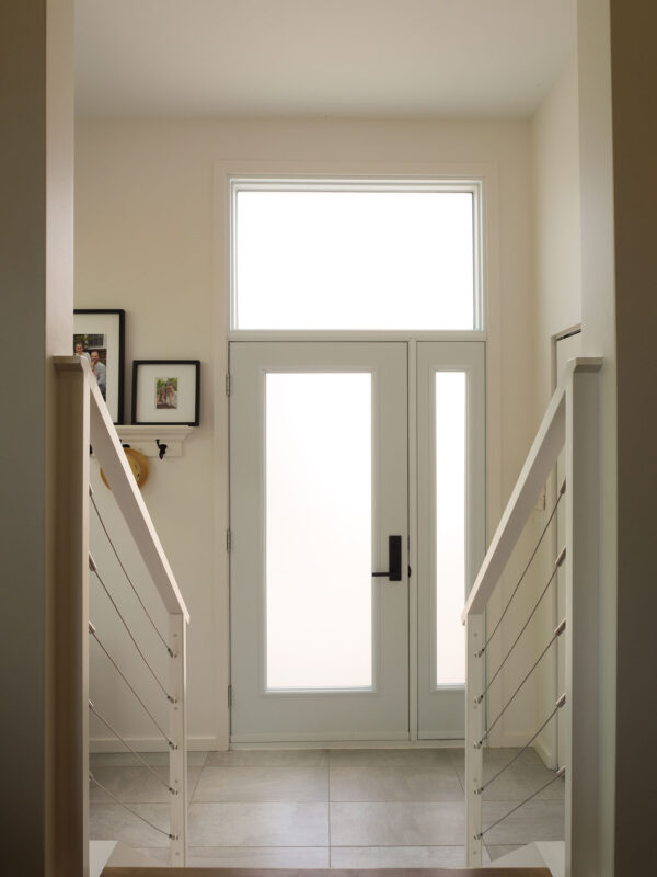 Interior view of modern glass entry door with natural light and cable railing staircase