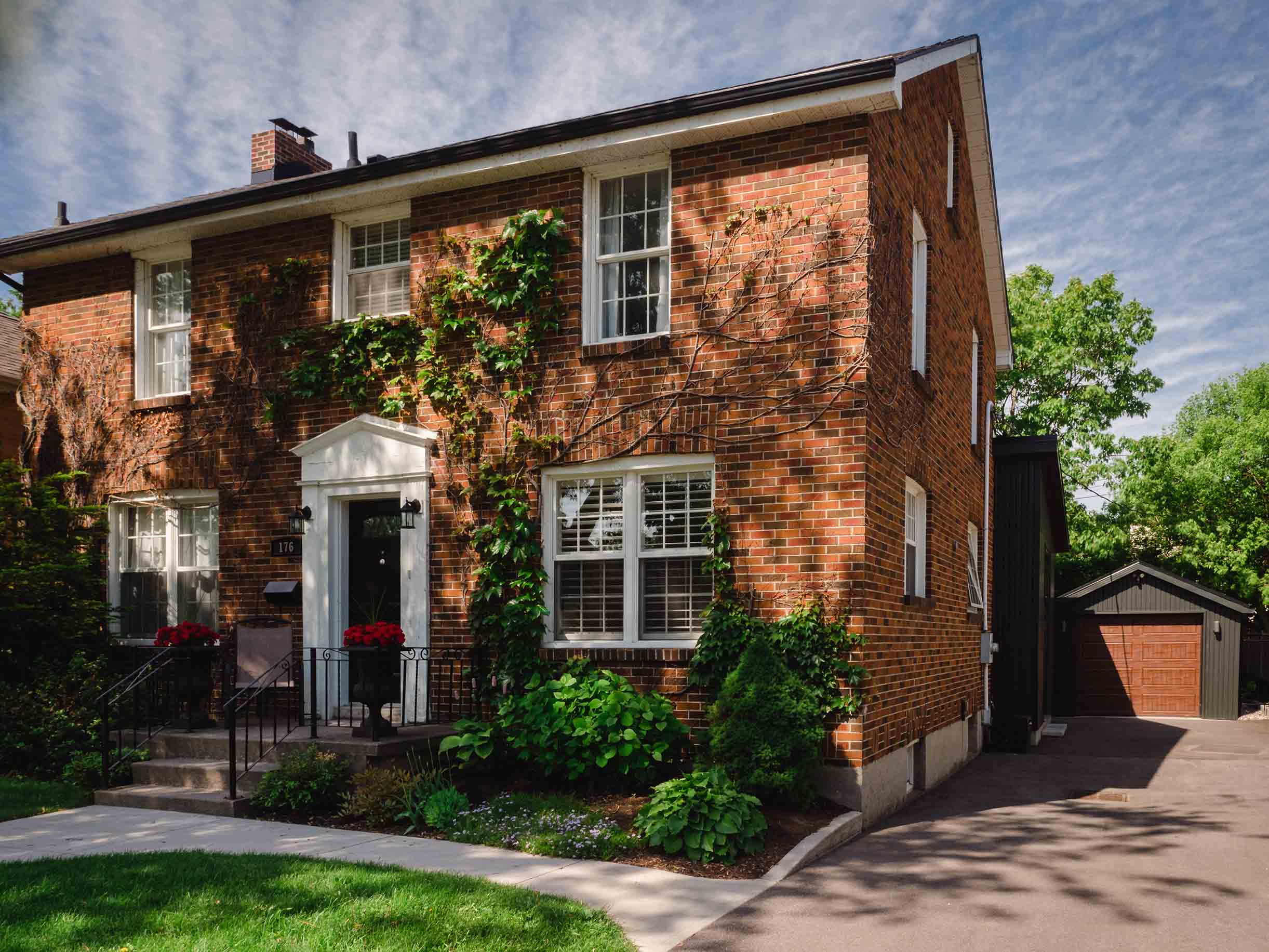 Front of home showing traditional brick facade with vines and white trim