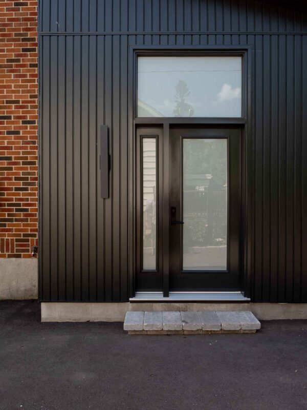 black metal-clad rear addition with glass door and transom window