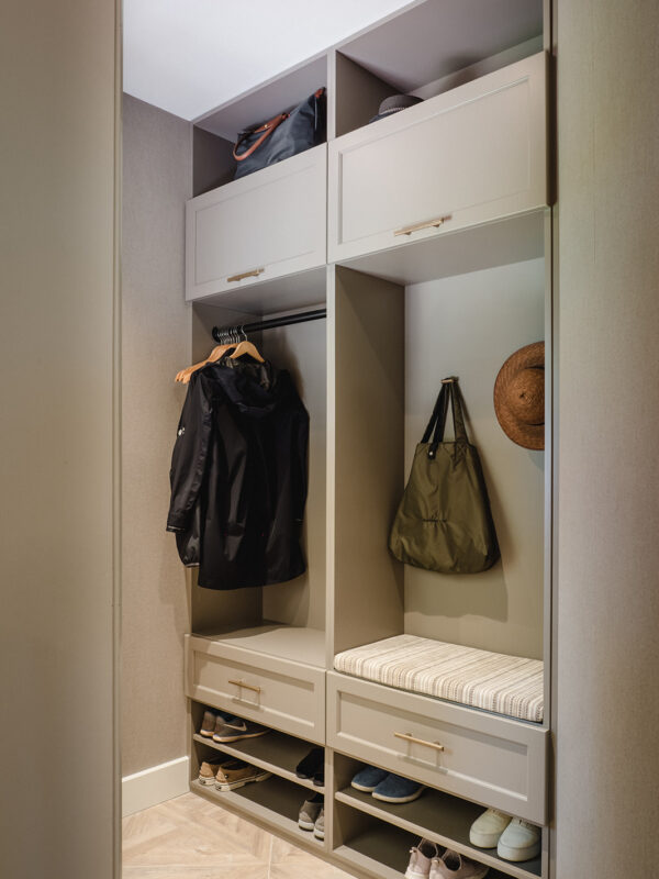 Custom cabinetry with open cubbies, shoe storage, bench seating, and coat hooks in a soft beige finish.
