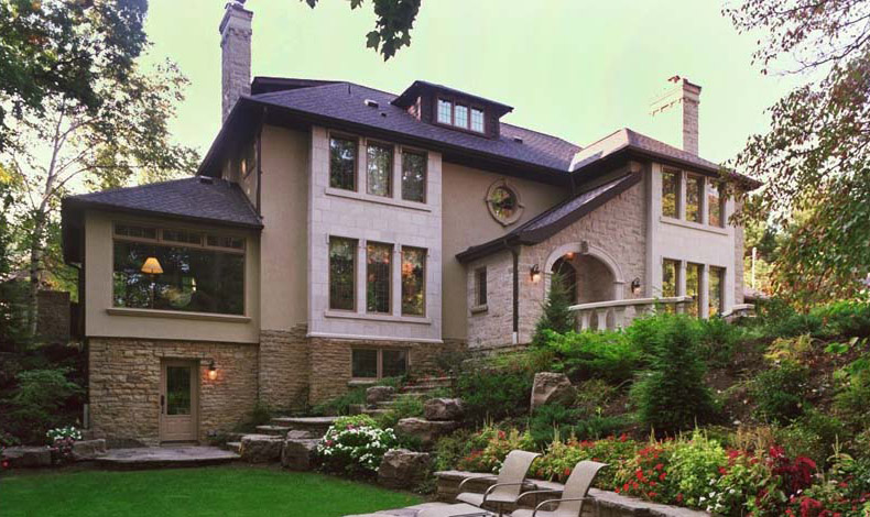 Backyard view of a luxury Toronto custom home with manicured gardens and natural stone landscaping.