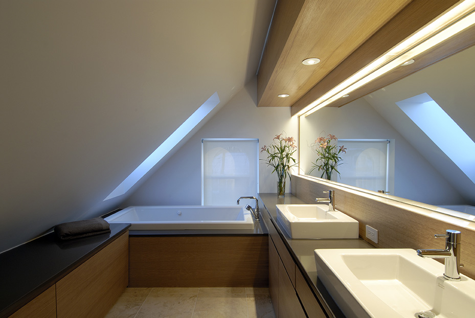 Modern attic bathroom with sloped ceilings, dual sinks, and wood detailing