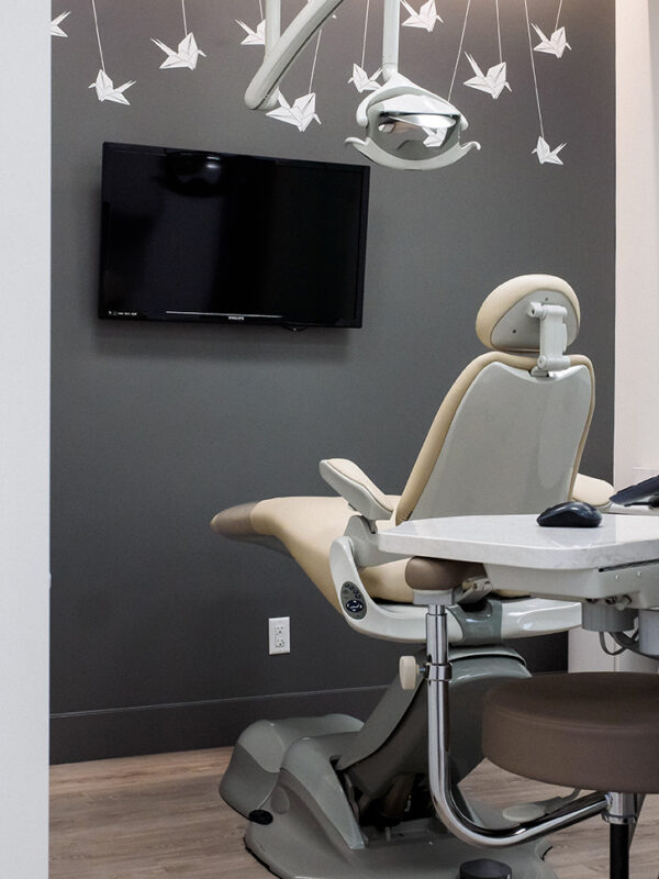 Dental treatment room featuring a beige exam chair and playful white origami crane mural.