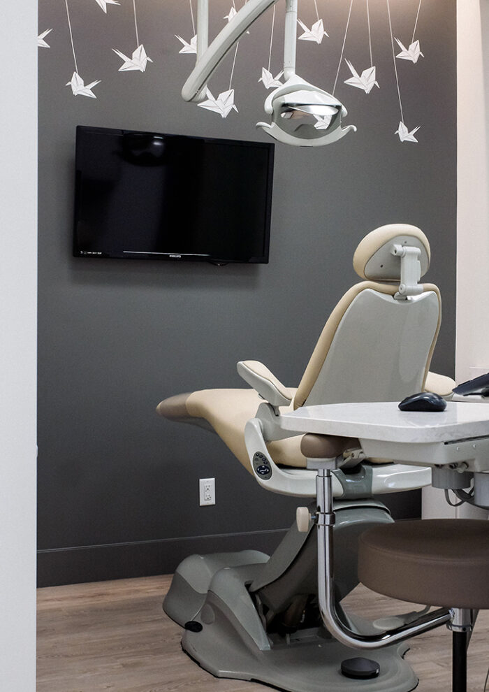 Dental treatment room featuring a beige exam chair and playful white origami crane mural.