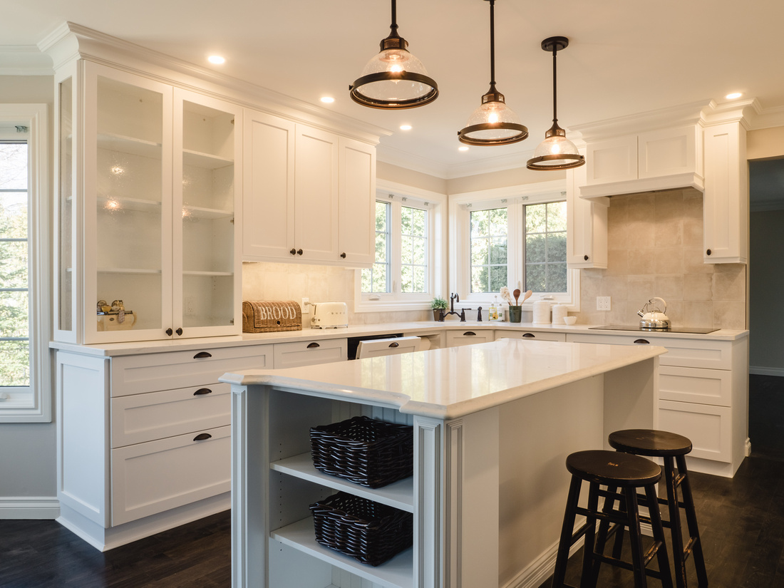 Wide view of renovated white kitchen with custom cabinetry and pendant lighting